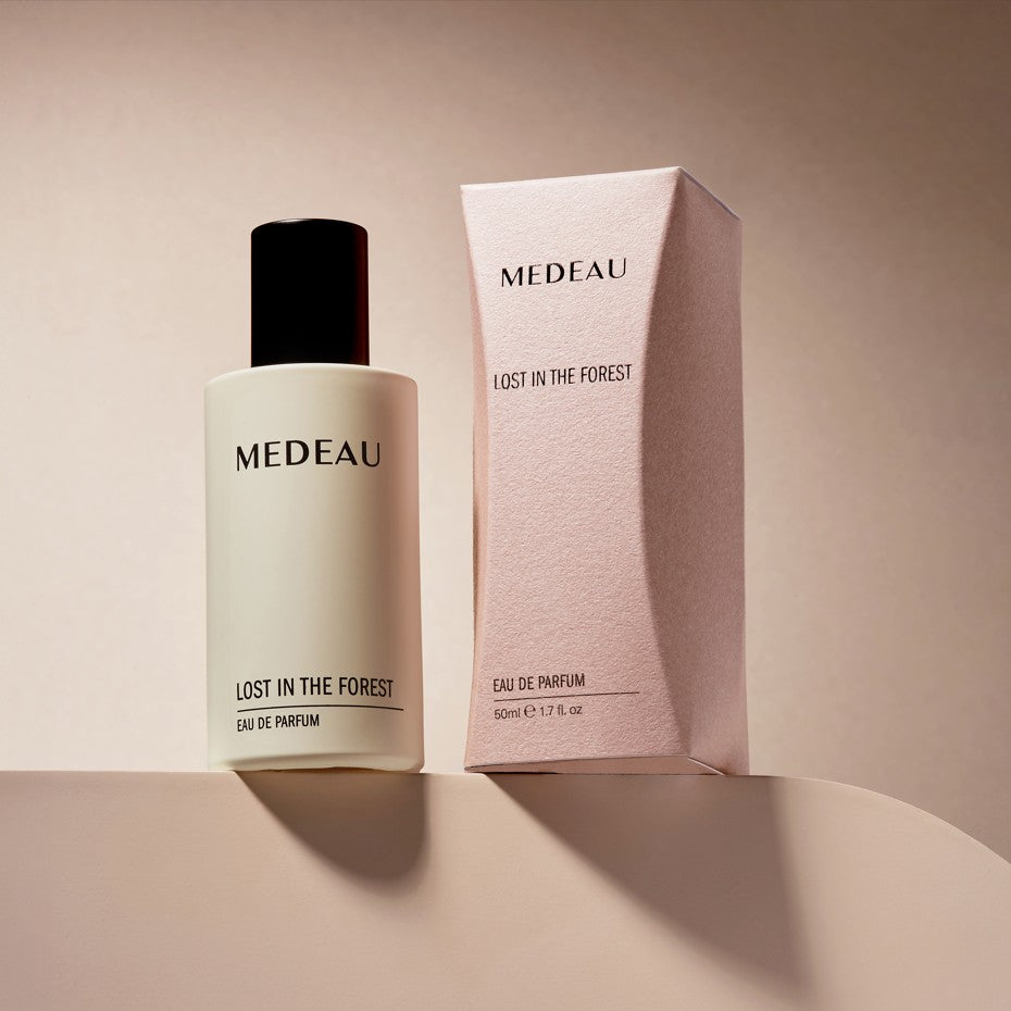MedEAU Lost In The Forest Eau De Parfum bottle standing next to its pink luxury product packaging box.