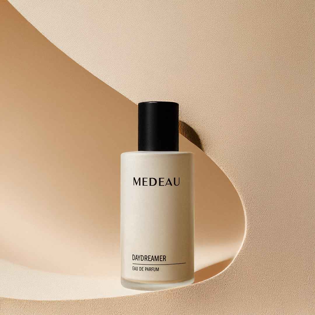 MedEAU Daydreamer Eau De Parfum bottle set against a minimalist curved beige backdrop.