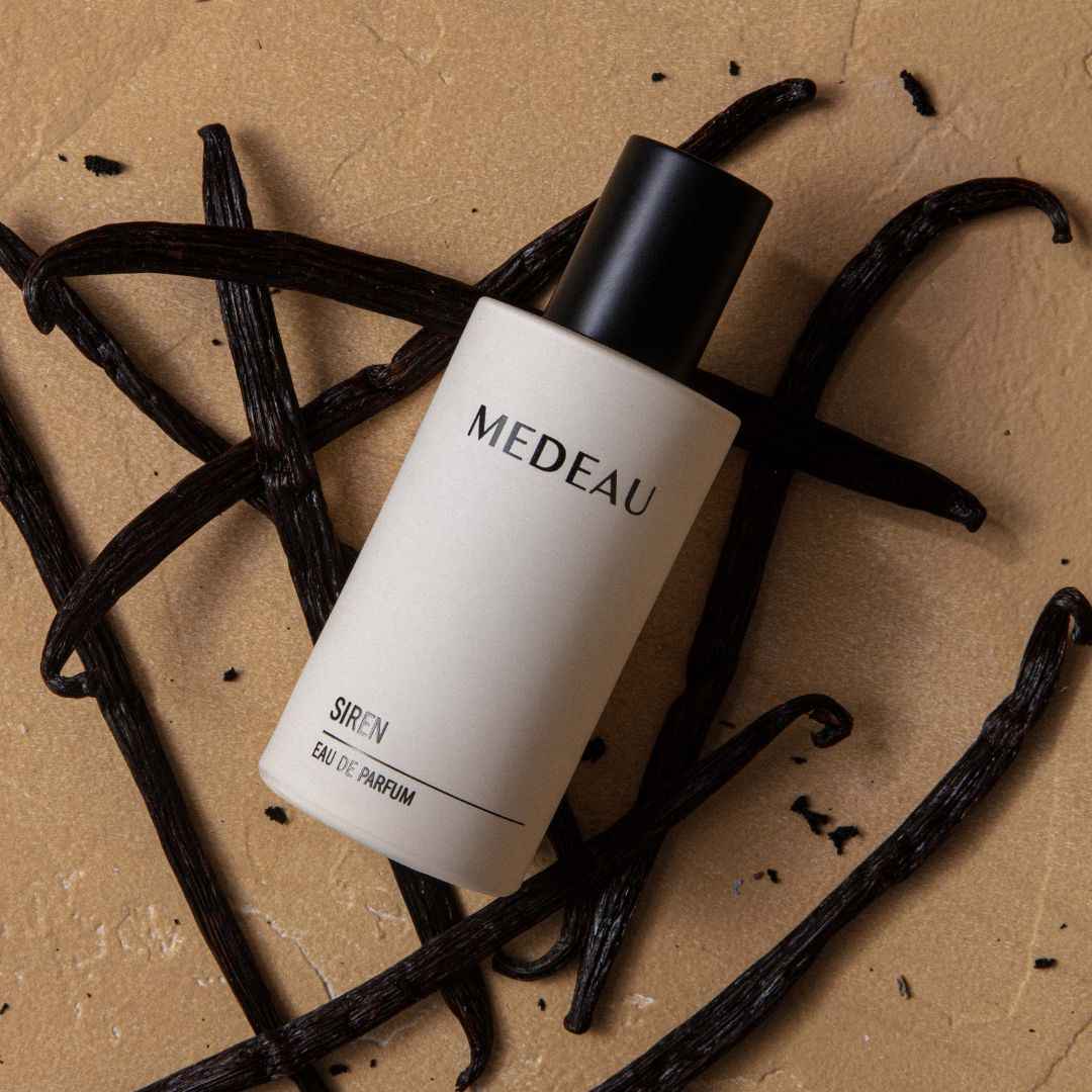 MEDEAU serum bottle on vanilla beans with a brown background